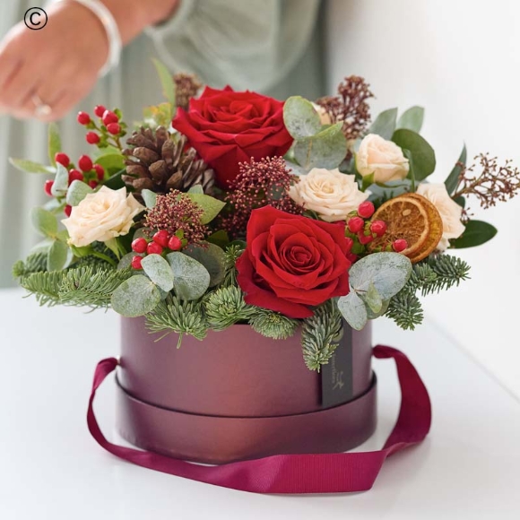 hatbox with blooms in red and green, and peach and cream highlights and pops of burgundy and cerise