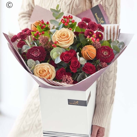 bouquet of blooms in red and green, with peach and cream highlights and pops of burgundy and cerise