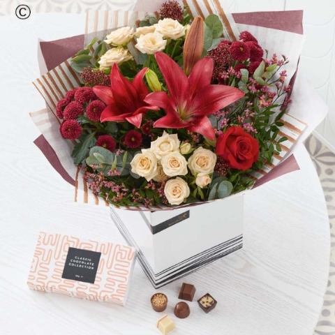 blooms in red and green, with peach and cream highlights and pops of burgundy and cerise, a festive gift card and chocolates